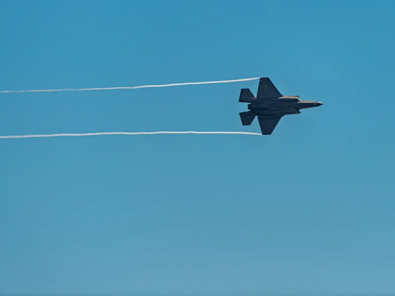 F-35A in level flight with thin white wingtip vapour trails stretching behind it
