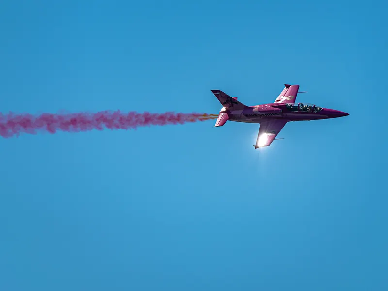 Red aerobatic jet trailing a vivid red smoke plume
