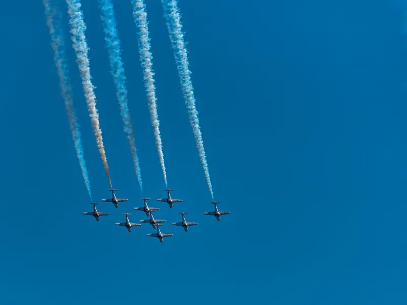 Snowbirds jets climbing in tight formation with parallel smoke columns