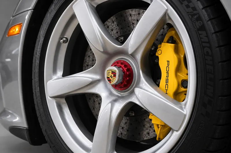 Close-up of a silver five-spoke wheel with a yellow brake caliper