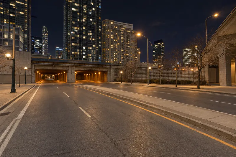 Empty city road at night leading toward illuminated downtown towers